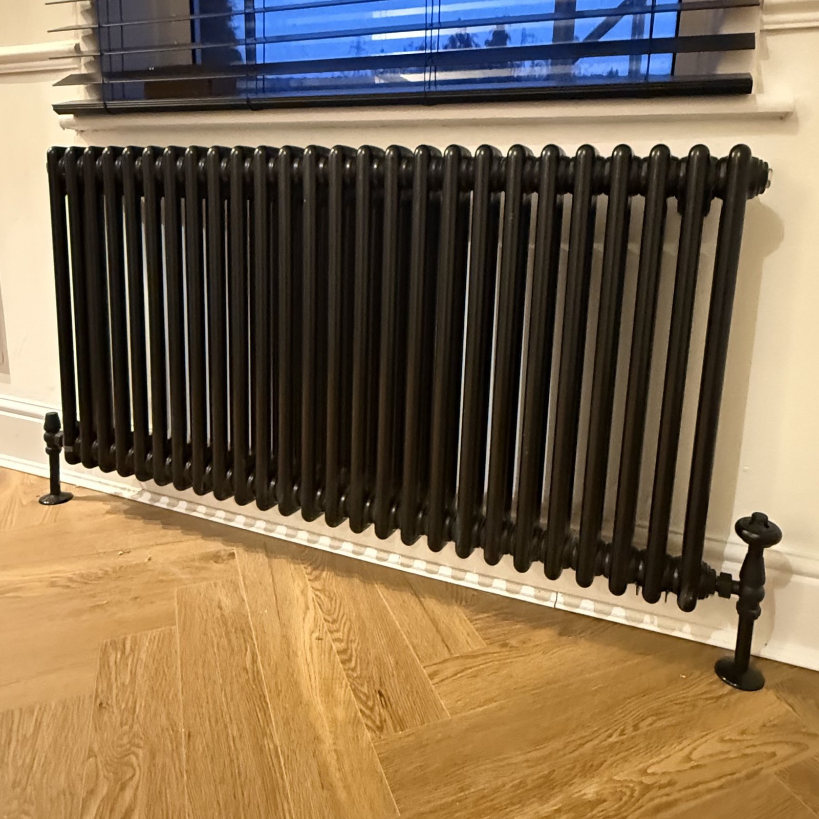 A sleek black radiator installed in a modern hallway